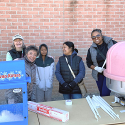 women smiling and laughing while they hand out cotton candy and snow cones