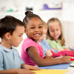 children smiling while colouring at desk
