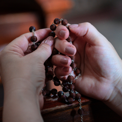 women's hands holding a rosary