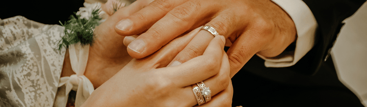 Close up of a couple's hands as they place rings on one another's fingers during a Wedding Mass